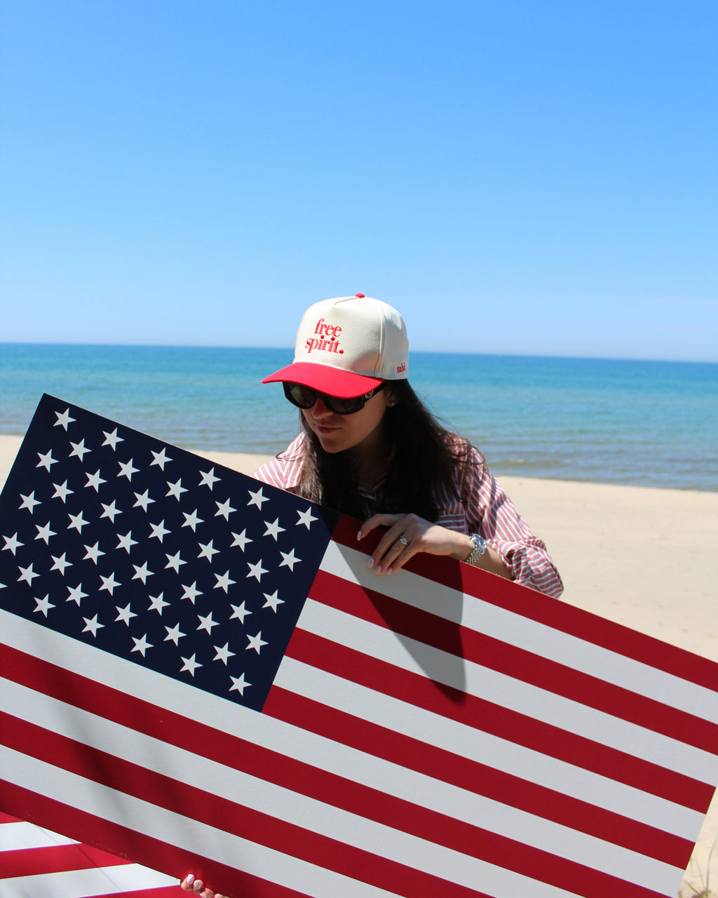 Person holding an American flag against a blue sky