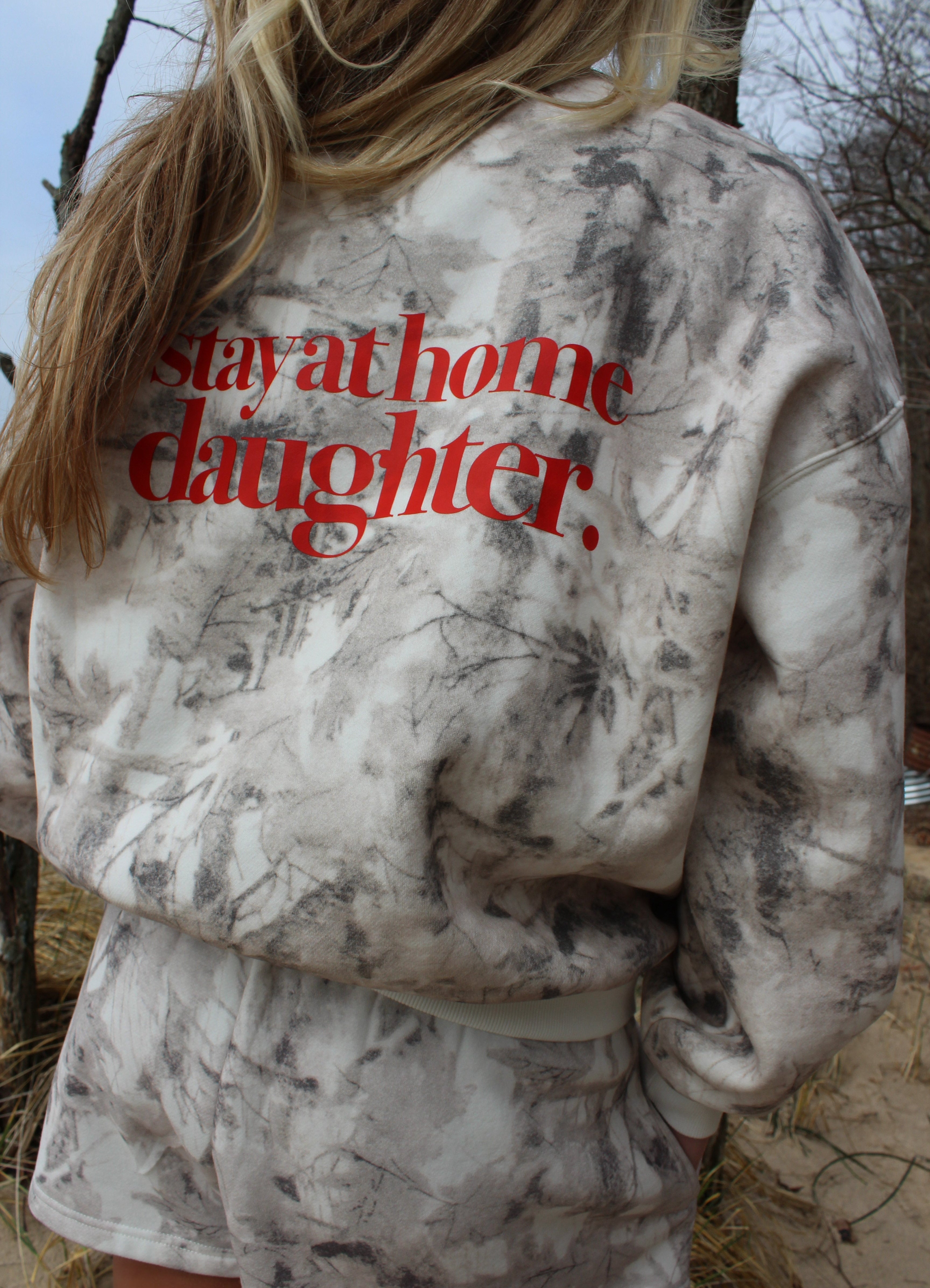 Person wearing a camouflage outfit with 'stay at home daughter' text on the back, standing outdoors.
