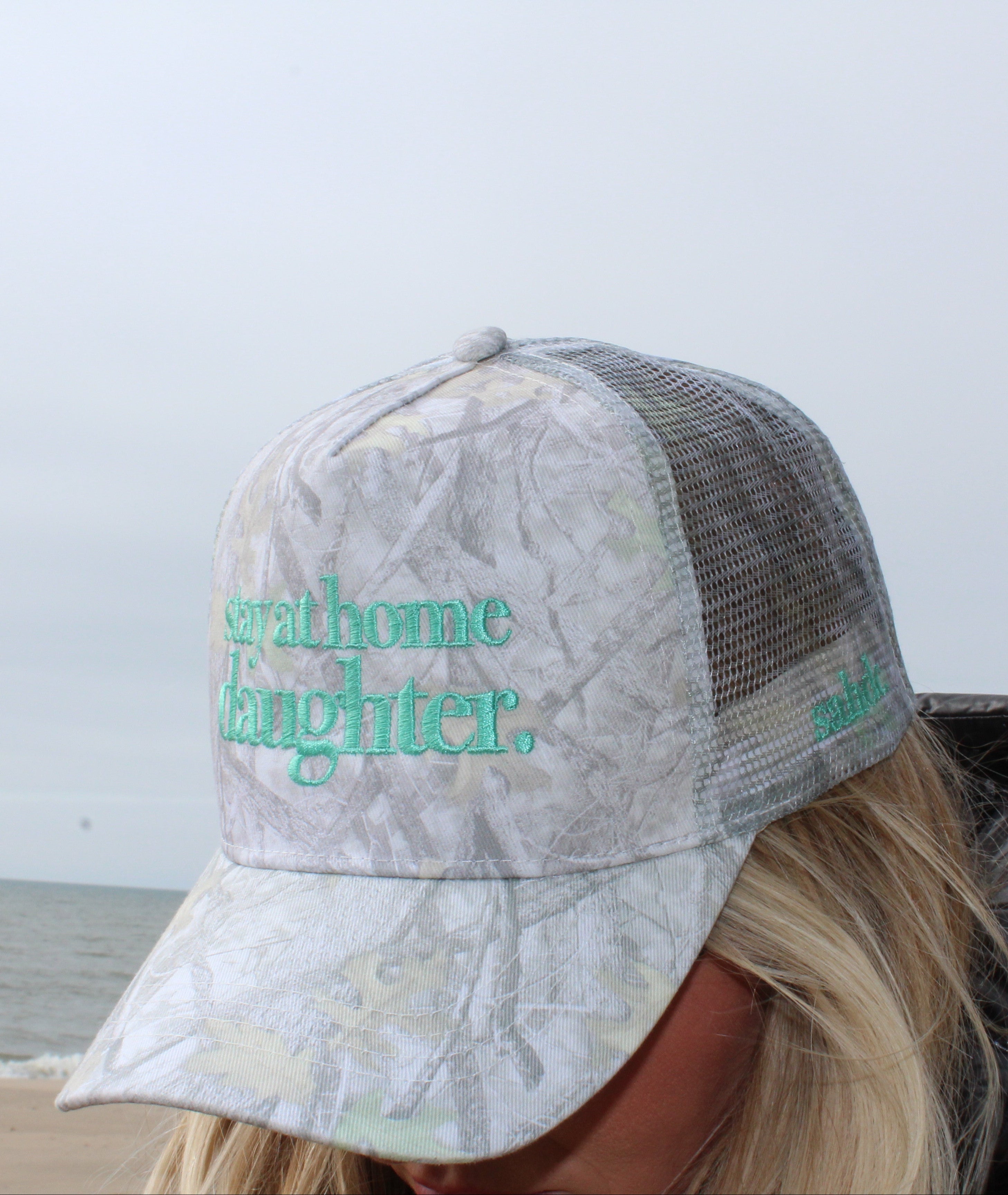 girl wearing stay at home daughter hat at the beach
