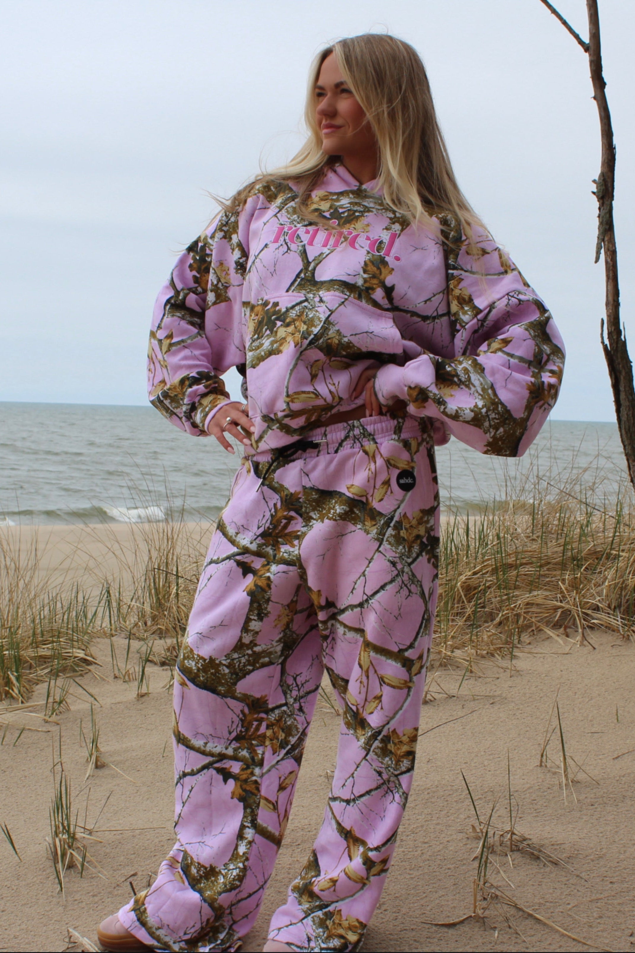 Person wearing pink camouflage sweatset on a beach.