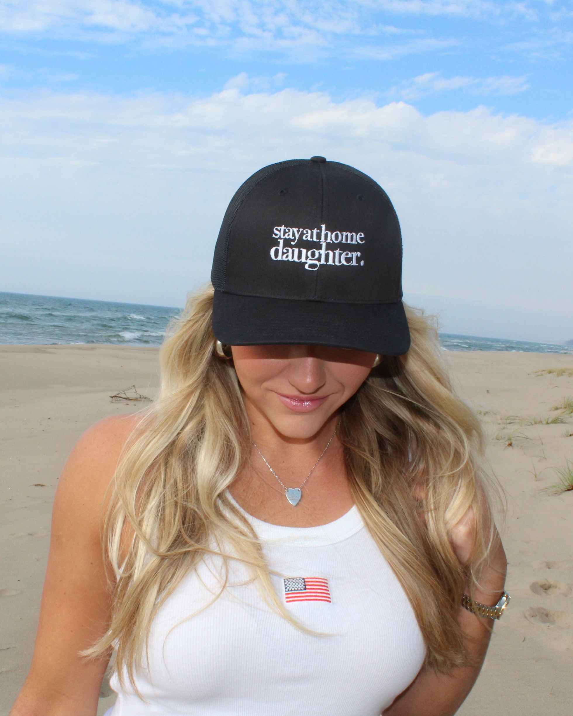 Woman wearing a black cap with stay at home daughter  text on a beach